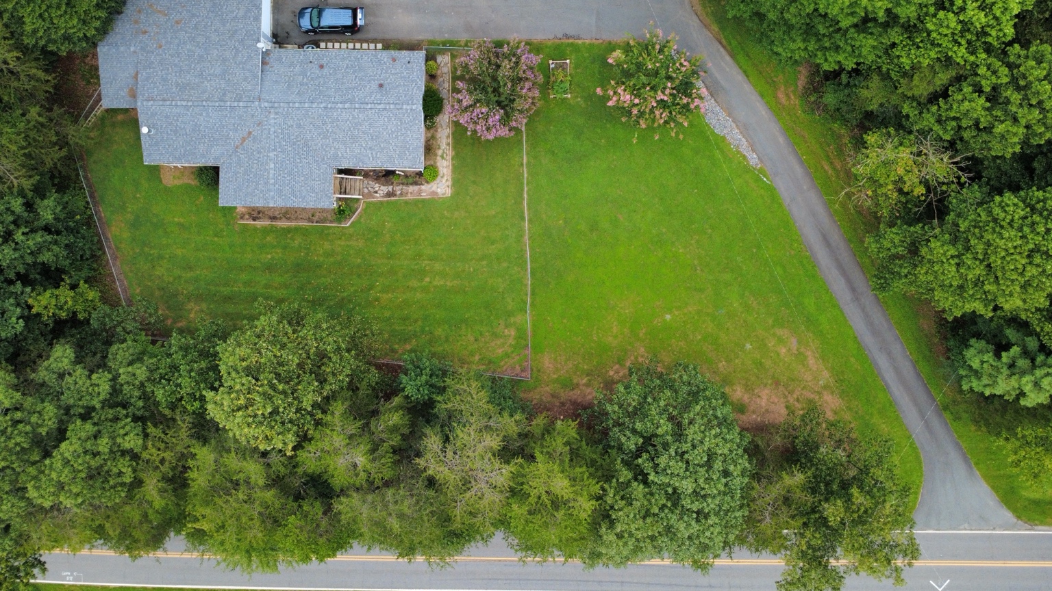 Overhead drone photograph of a house, lawn, and surrounding roads